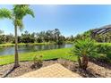 Paver patio and lush landscaping overlooking the serene water view creates a relaxing outdoor space at 608 Crane Prairie Way, Osprey, FL 34229