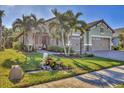Green home with large front yard, palm trees, and three-car garage at 11897 Hunters Creek Rd, Venice, FL 34293