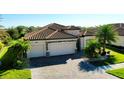 Aerial view of a home with tile roof, paver driveway, and three-car garage at 20460 Granlago Dr, Venice, FL 34293