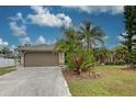 Tan house with attached garage and a spacious front yard at 23102 Madelyn Ave, Port Charlotte, FL 33954