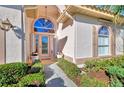 Welcoming front entry with arched doorway and lush landscaping at 2331 Harrier Way, Nokomis, FL 34275