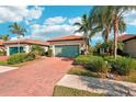 Single-story home with a light green garage door and brick driveway at 2572 Daisy Dr, North Port, FL 34289