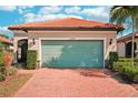 Single-story home with a light green garage door and brick driveway at 2572 Daisy Dr, North Port, FL 34289