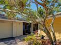 Inviting home entrance with decorative shrubbery, trees, and a two car garage on the left at 263 Southampton Dr # 301, Venice, FL 34293