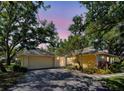 Charming yellow home with a tile roof, lush landscaping, and a spacious two-car garage at dusk at 263 Southampton Dr # 301, Venice, FL 34293
