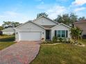 Single-story home with a white exterior, brick driveway, and landscaping at 486 Chubut Ct, Punta Gorda, FL 33983