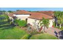Inviting exterior showcasing a well-manicured lawn, lush landscaping, and a home with a clay tile roof at 5584 Cantucci St, Nokomis, FL 34275