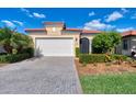 Front view of a single-story house with a white garage door and brick driveway at 10428 Crooked Creek Dr, Venice, FL 34293