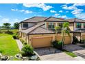 Two-story townhome with tile roof, attached two-car garage, and lush landscaping under a bright blue sky at 20100 Ragazza Cir # 101, Venice, FL 34293