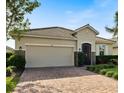 Tan single-Gathering home with tile roof, two-car garage, and paver driveway at 2049 Mesic Hammock Way, Venice, FL 34292