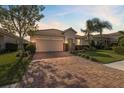 Single-Gathering home with tile roof, two-car garage, and paver driveway at dusk at 2049 Mesic Hammock Way, Venice, FL 34292