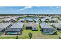 An aerial view of a residential community with houses featuring pools and a central pond at 26069 Norman Dr, Englewood, FL 34223