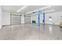 Bright garage interior with epoxy flooring, two garage doors, and a car lift at 4130 Rock Creek Dr, Port Charlotte, FL 33948