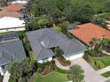 Aerial view of a home with a tile roof, lush landscaping, and a paver driveway in a golf community at 589 Pond Willow Ln, Venice, FL 34292