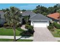 Charming home featuring a well-manicured lawn, tile roof, and paver driveway leading to a two-car garage at 589 Pond Willow Ln, Venice, FL 34292