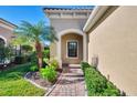 Brick walkway to covered entryway with arched window and lush landscaping at 11539 Okaloosa Dr, Venice, FL 34293