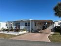 Front exterior view of a mobile home with a covered carport and landscaping at 708 Roma Rd, Venice, FL 34285