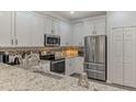 Well-lit kitchen featuring stainless steel appliances, granite countertops, and white cabinetry at 9855 Haze Dr, Venice, FL 34292