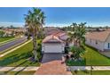 Beautifully landscaped home featuring a well-maintained lawn, mature palms, and a brick-paved driveway at 11679 Anhinga Ave, Venice, FL 34292