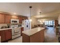 Charming kitchen with wood cabinets, white appliances, an island, and a view of the living room at 2260 Stickney Point Rd # 303, Sarasota, FL 34231