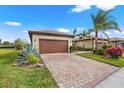 Elegant single-story home with a brick driveway, a two-car garage, and lush green landscaping at 12837 Oriago St, Venice, FL 34293