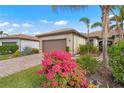 Inviting single-story home boasts a lush front yard with vibrant flowers and beautiful tropical landscaping at 12837 Oriago St, Venice, FL 34293
