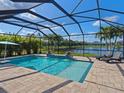 Screened-in pool area with brick pavers and a scenic view of the lake at 5930 Anise Dr, Sarasota, FL 34238