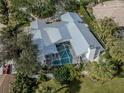 Aerial view of home with metal roof, screened pool, chimney, mature landscaping and white picket fence at 705 Armada N Rd, Venice, FL 34285
