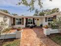 Inviting red brick front porch with seating and beautiful landscaping creates a welcoming entrance at 705 Armada N Rd, Venice, FL 34285