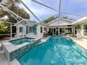 Screened in pool and spa with light blue tiles, surrounded by seating area and white exterior of home at 705 Armada N Rd, Venice, FL 34285