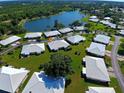 Aerial view of a lakeside neighborhood with white-roofed villas surrounded by lush greenery and trees at 3117 Heron Shores Dr, Venice, FL 34293