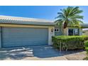 Attached two-car garage with gray doors and a manicured shrub on a sunny single story villa at 3117 Heron Shores Dr, Venice, FL 34293