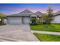 Beautiful single-story home with a paved driveway, a three-car garage, and attractive landscaping at 19807 Bridgetown Loop, Venice, FL 34293