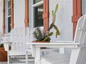 Up-close view of white wooden Adirondack chairs, with a small white table with succulents on a textured patio at 1423 Avenida Del Circo # 1C, Venice, FL 34285