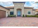 Inviting front exterior featuring a well-maintained lawn, brick driveway, and elegant blue double-door entrance at 400 Maraviya Blvd, Nokomis, FL 34275