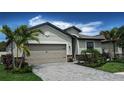 Beautiful home showcasing a paved driveway and lush landscaping under a bright blue sky at 19716 Fishhawk Trl, Venice, FL 34293