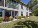 A view of the backyard featuring a screened in porch and balcony with decorative landscaping at 936 Capri Isles Blvd # 102, Venice, FL 34292