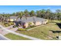 Beautiful property featuring lush lawn, mature trees, complemented by brick driveway, and American flag at 13542 Abercrombie Dr, Englewood, FL 34223