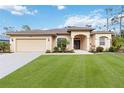 Charming single-story home featuring manicured lawn, beige stucco, arched entry and two-car garage at 1684 Ruiz St, North Port, FL 34286