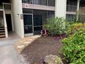 Condo front entrance featuring screened in patio and decorative landscaping at 634 Bird Bay E Dr # 103, Venice, FL 34285
