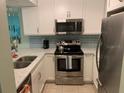 Renovated kitchen features white cabinets, stainless steel appliances, and stone countertops at 634 Bird Bay E Dr # 103, Venice, FL 34285