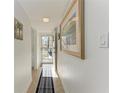 Hallway featuring a neutral tile floor, artwork, and a view of the front door at 110 Vista Hermosa Cir # 102B, Sarasota, FL 34242