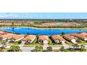 Aerial view of single Gathering home with brick drive and tile roof, lake view and mature landscaping at 10466 Medjool Dr, Venice, FL 34293