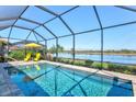 Screened pool with waterfront view, lounge chairs and sun umbrella on brick paver patio at 10466 Medjool Dr, Venice, FL 34293