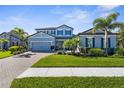 Beautiful two-story home featuring a lush green lawn, tropical palm trees, and brick driveway at 19836 Bridgetown Loop, Venice, FL 34293