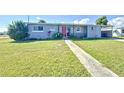 Inviting single-story home featuring a lush lawn, sidewalk, and an eye-catching red front door at 7903 Hyde Park Ave, North Port, FL 34287