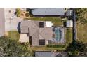 Aerial view of a home with a screened-in pool, solar panels, and mature trees at 888 Guild Dr, Venice, FL 34285