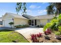 Charming single-story home with a well-manicured lawn, mature trees, and attached two-car garage at 888 Guild Dr, Venice, FL 34285