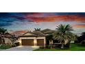 Charming home featuring a two-car garage, stone accents, tile roof, and a lush green lawn at 13238 Famiglia Dr, Venice, FL 34293