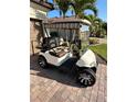 Tan golf cart featuring comfortable patterned seats and chrome wheels parked on a brick driveway at 13730 Vancanza, Venice, FL 34293